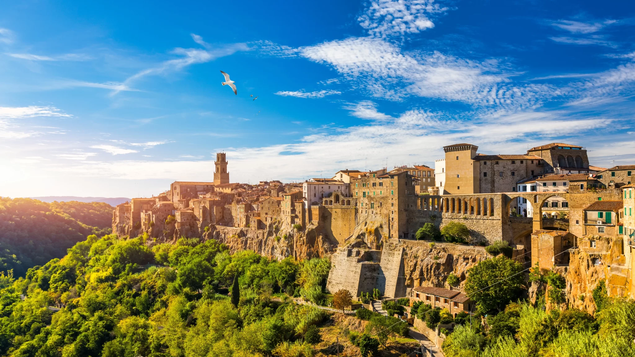 Vista panoramica di Pitigliano con edifici storici su una scogliera al tramonto.