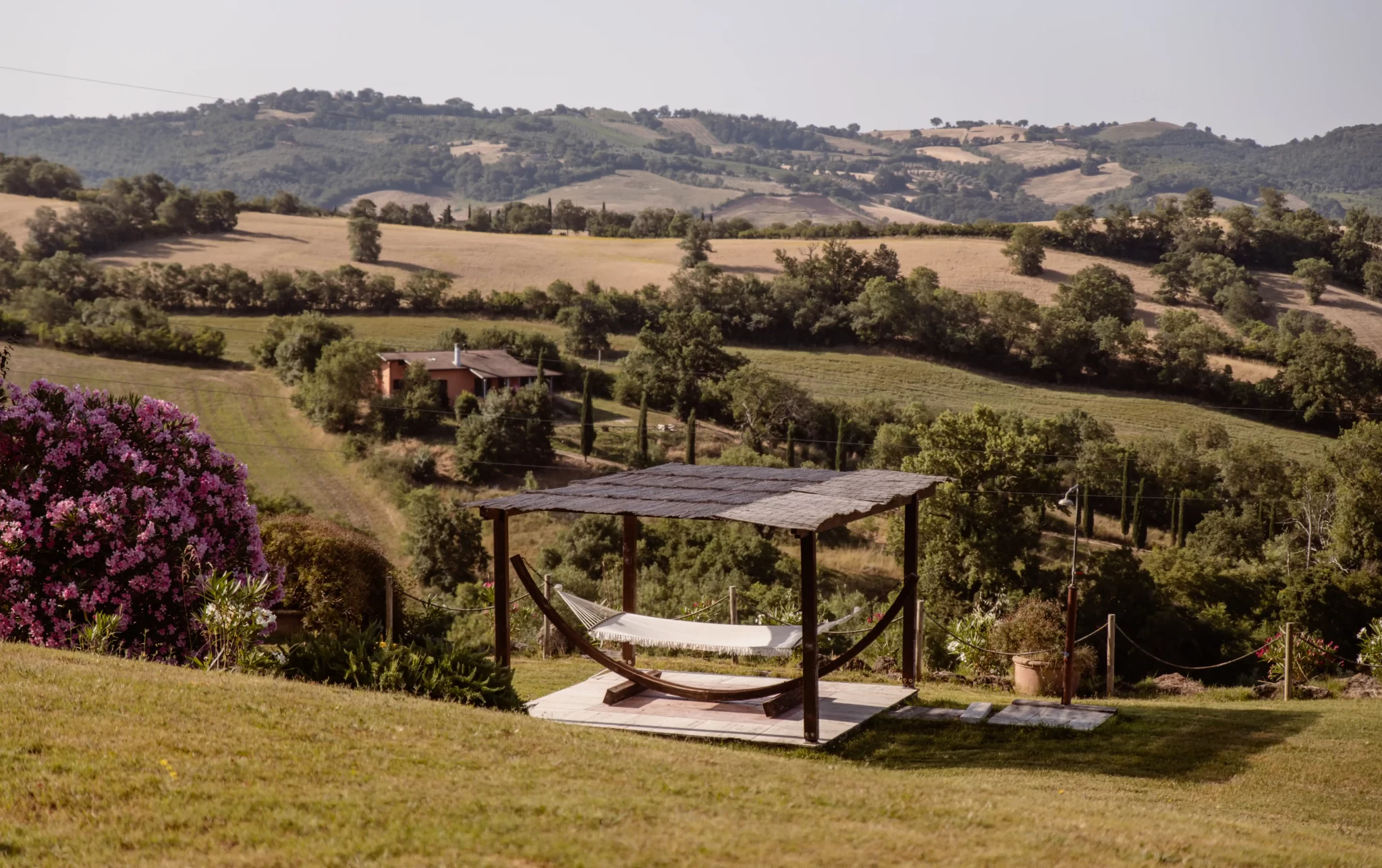 Amaca all'aperto con vista su colline toscane e campagna verde.