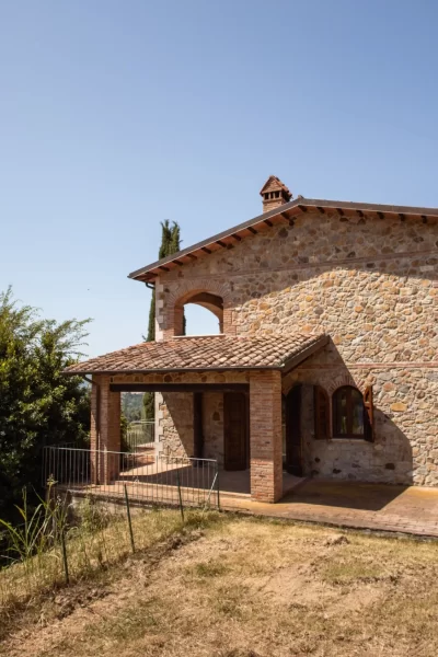 Casa in pietra rustica immersa in un paesaggio collinare durante una giornata serena.