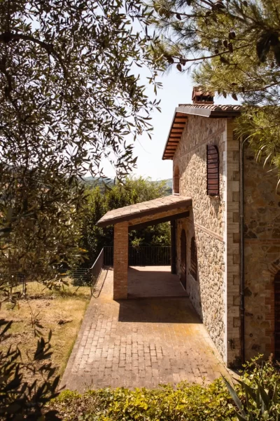 Casale in pietra immerso nel verde con alberi e arbusti circostanti.