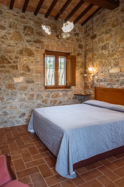 Camera da letto rustica con pareti in pietra e letto matrimoniale.