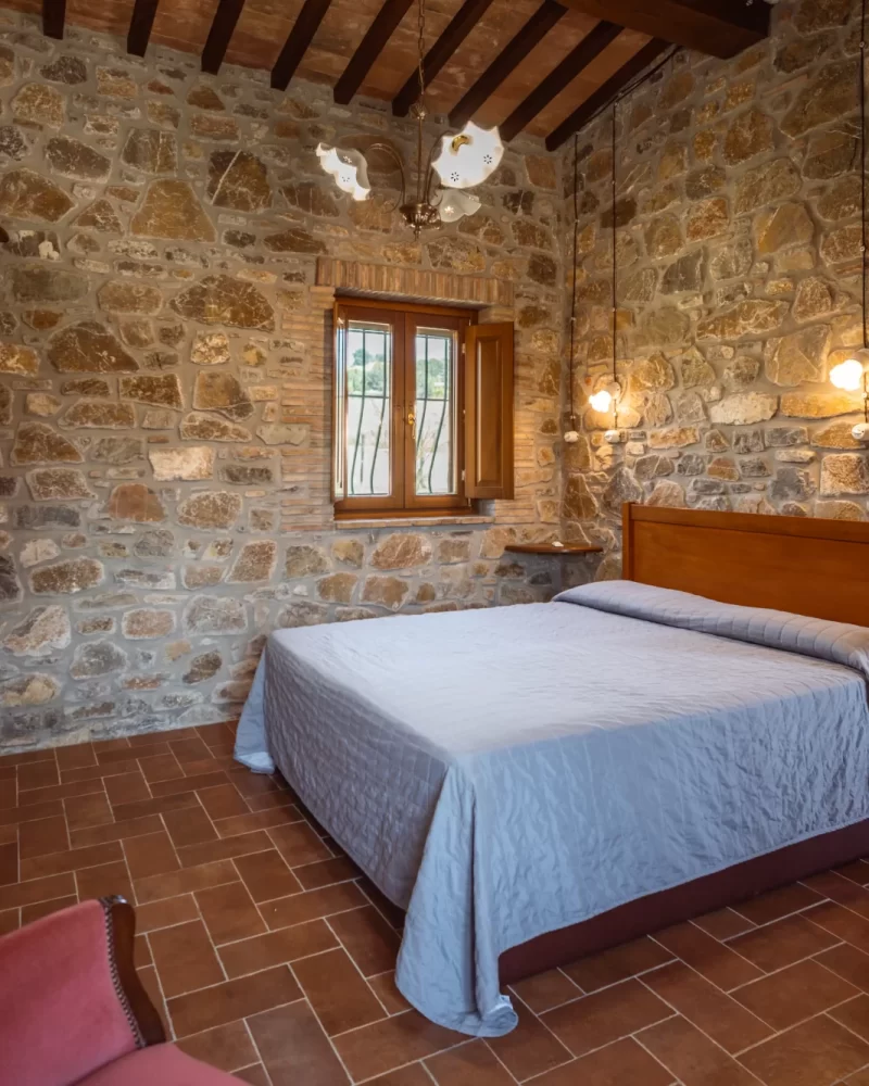 Camera da letto rustica con pareti in pietra e letto matrimoniale.