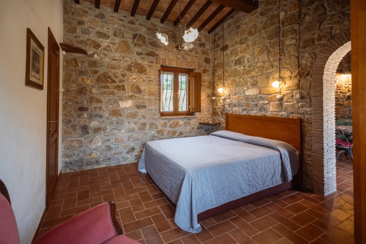 Camera da letto rustica con pareti in pietra e letto matrimoniale.