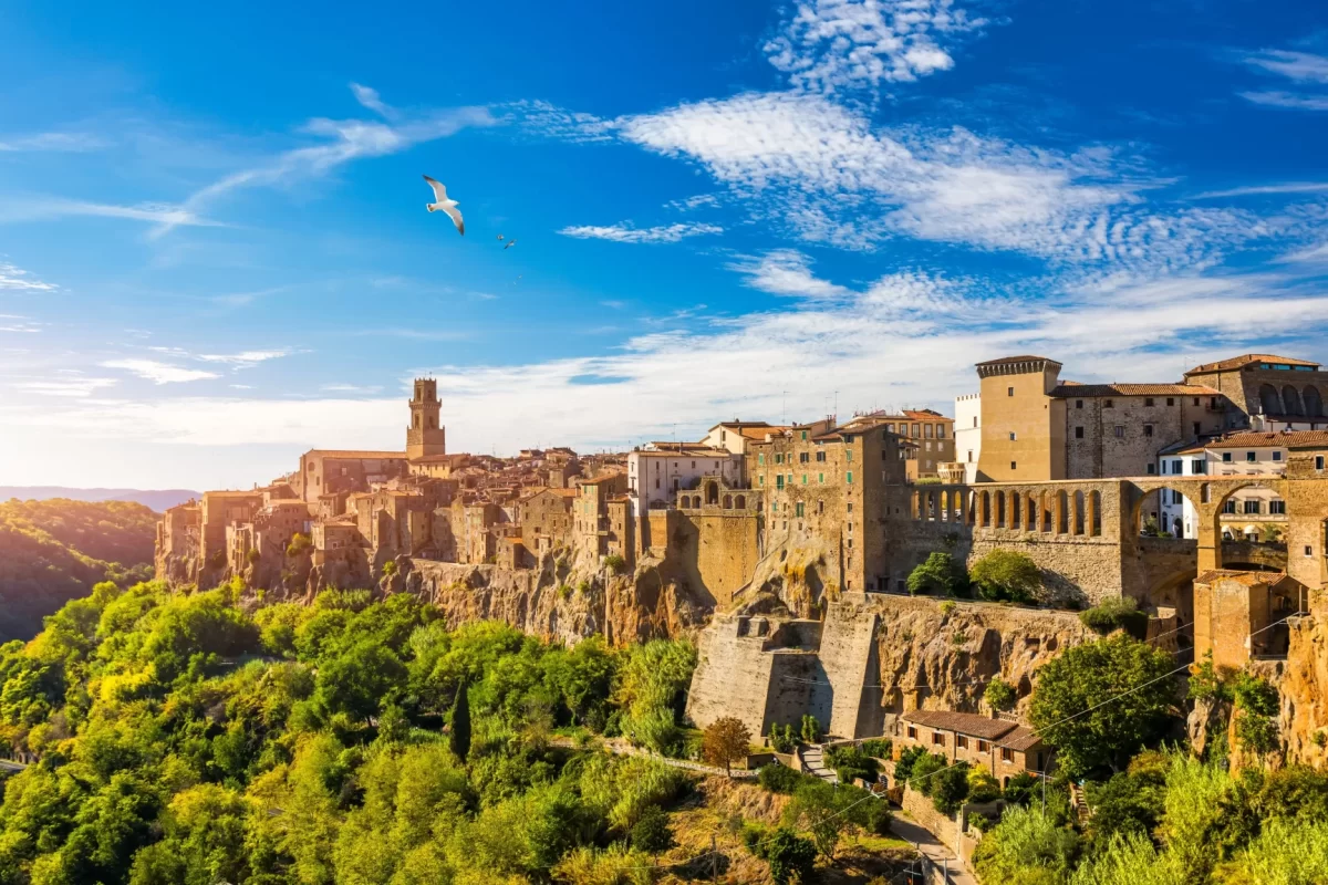 Vista panoramica di Pitigliano con edifici storici su una scogliera al tramonto.