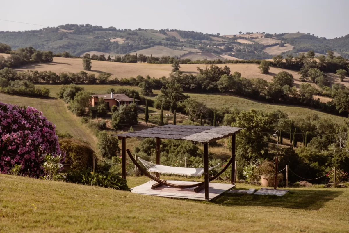 Amaca all'aperto con vista su colline toscane e campagna verde.
