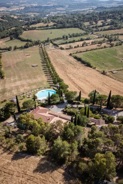 Vista aerea di una villa con piscina immersa in un paesaggio rurale.