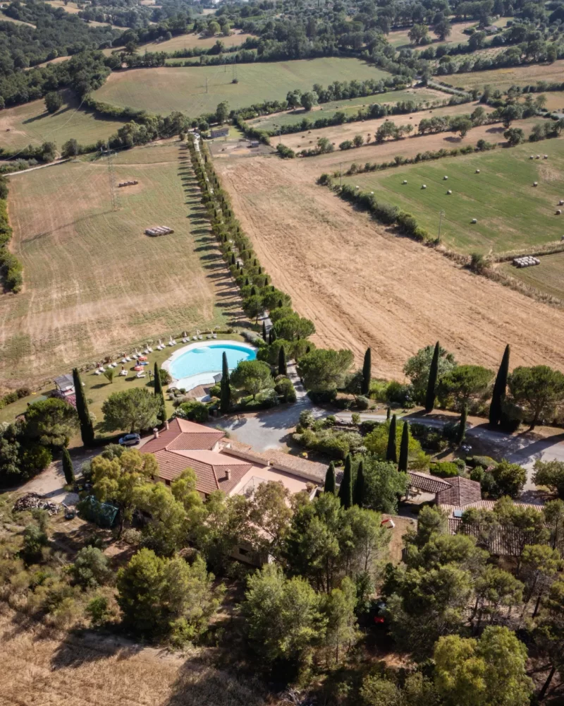 Vista aerea di una villa con piscina immersa in un paesaggio rurale.