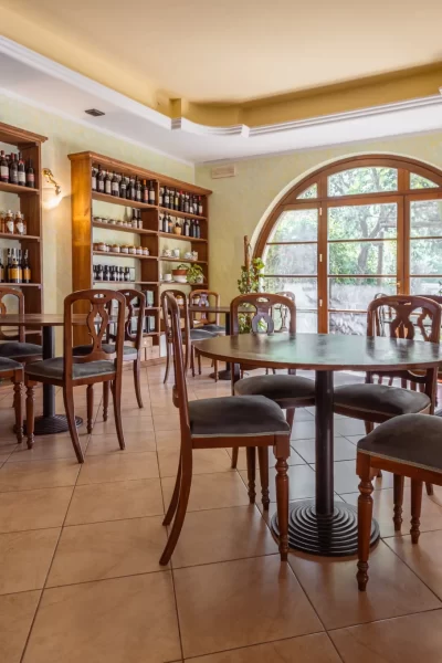 Sala da pranzo accogliente con tavoli di legno e pareti decorate con scaffali di bottiglie di vino.