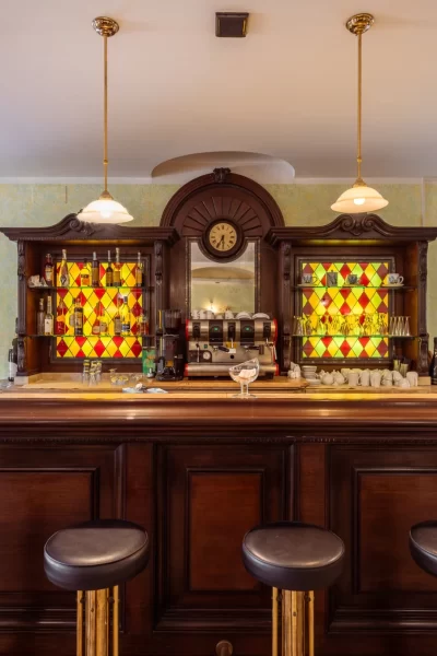 Bar vintage con bancone in legno scuro e vetrine colorate.