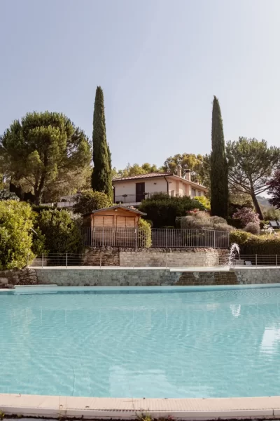 Piscina all'aperto con giardino e villa sullo sfondo.