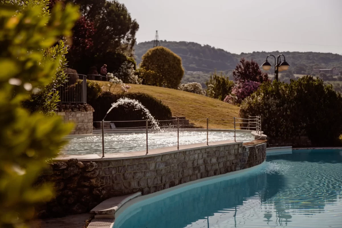 Piscina con cascata in un giardino paesaggistico al tramonto.