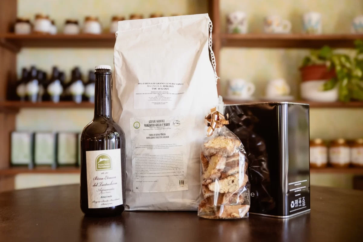 Bottiglia di birra, sacco di farina, biscotti e scatola di t&egrave; su un tavolo di fronte a uno scaffale.