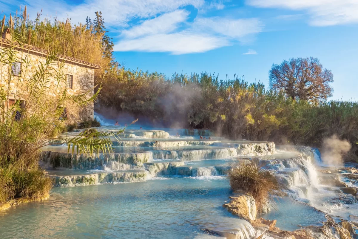 Cascate termali di Saturnia immerse nella natura con un casolare in pietra.