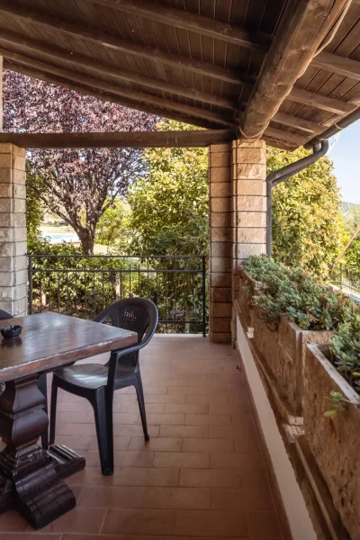Veranda con tavolo e sedie affacciata su un giardino verdeggiante con vista panoramica.