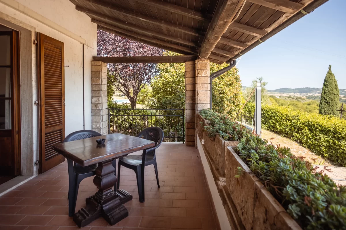 Veranda con tavolo e sedie affacciata su un giardino verdeggiante con vista panoramica.