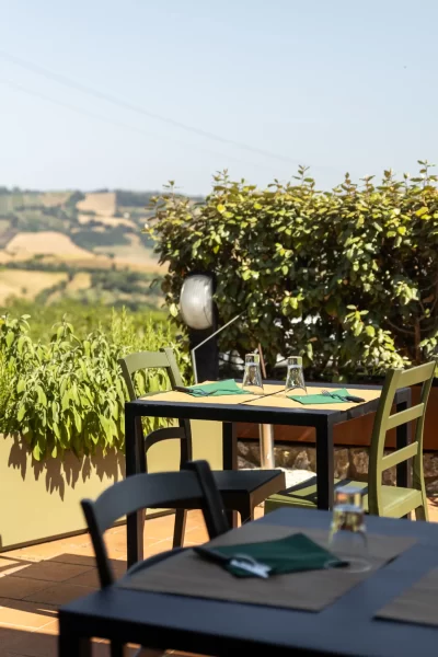 Tavolini apparecchiati su una terrazza con vista panoramica sulla campagna.
